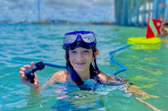 smiling girl in large pool learning how to use Nemo dive system