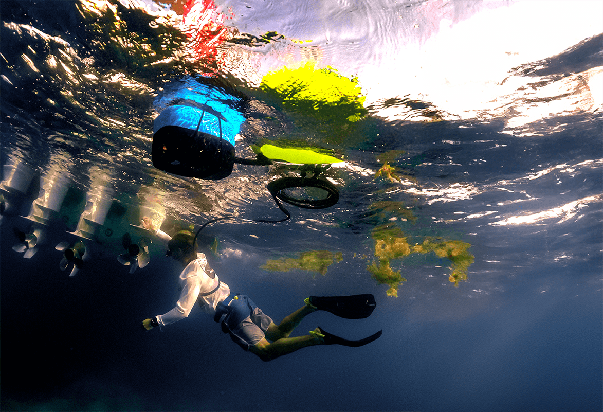 nomad-mini-hull-cleaning Diver inspecting a boat propeller underwater using the BLU3 Nomad Mini dive system, with the system hose extending from the surface.