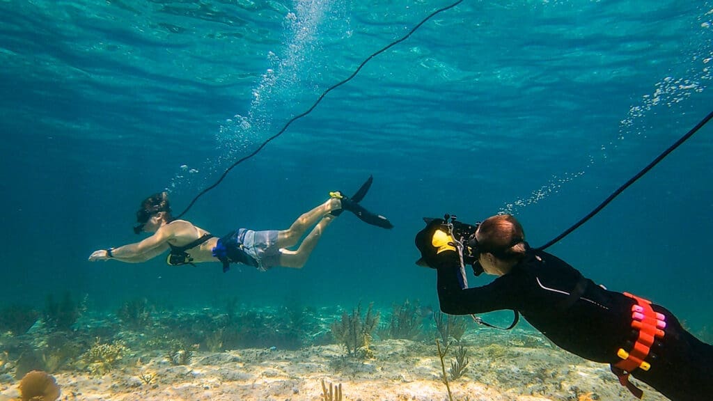 A photographer takes underwater photos while using BLU3 Nomad tankless dive system.