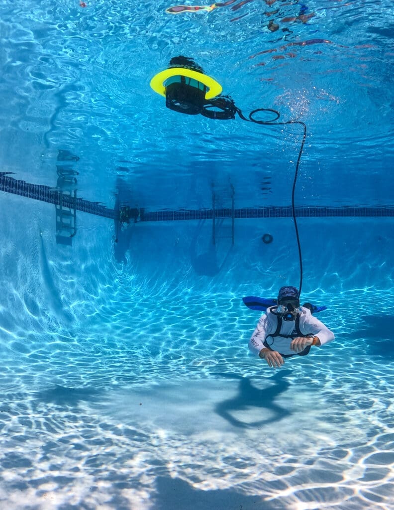 A person uses BLU3 Nomad Mini to breathe underwater in a swimming pool without scuba gear.