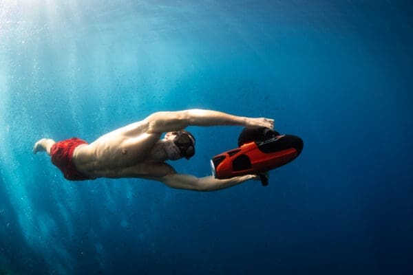 Man using Sublue Vapor underwater scooter while snorkeling in clear blue ocean